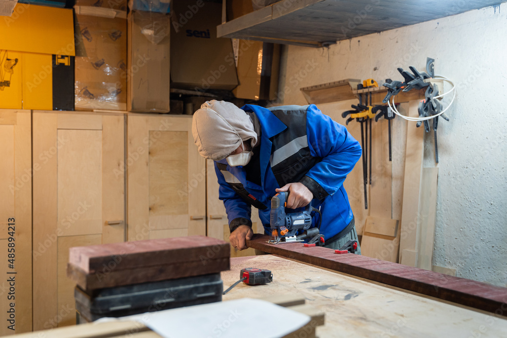 Worker in coverall and respirator. Craftsman holding wooden boards and working in workshop. Craftsmanship, production concept. Worker in coverall and respirator. Craftsman holding wooden boards and working in workshop. Craftsmanship, production concept.