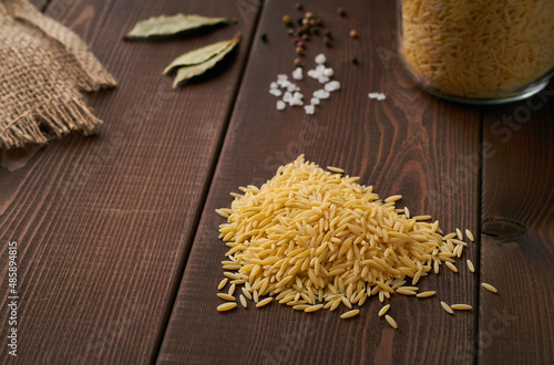 pile of uncooked risoni orzo pasta italian cuisine on brown background photo