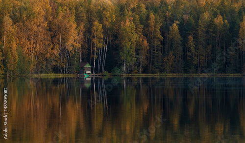 fishing shelter in autumn evening on the forest lake
