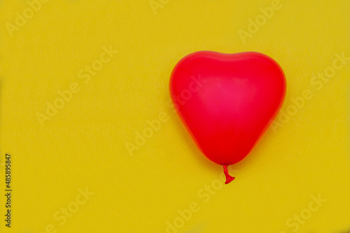 A balloon in the form of a red heart on a yellow background. Valentine's day. Love.
