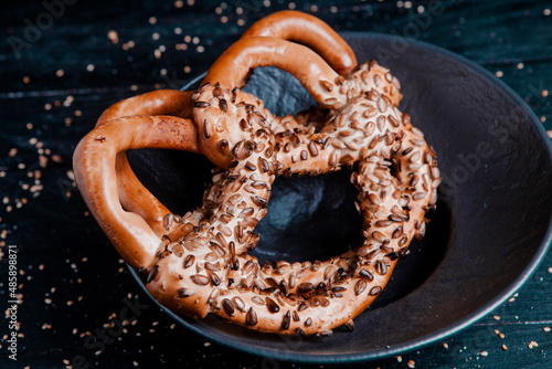 Fresh prepared homemade soft pretzels. Different types of baked bagels with seeds on a black background.