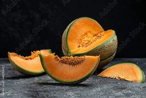 Whole and sliced of Japanese melons or cantaloupe on dark background. place for text