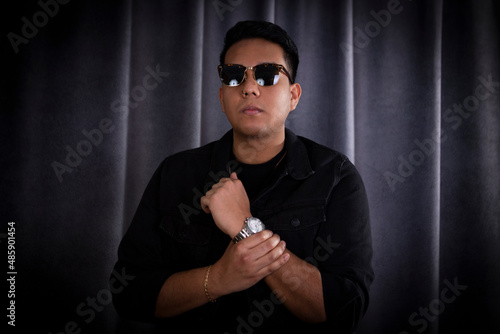 Young latin man in his twenties poses for a studio portrait. His holds his arm and fist as signal of power and contro photo