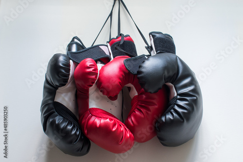 Some red and black boxing gloves hanged on the wall