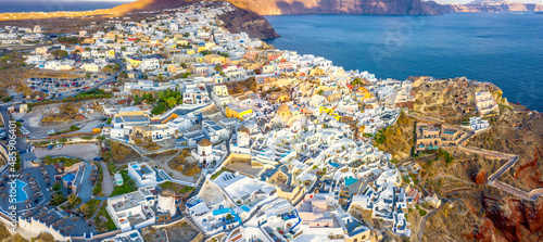 Picturesque Aerial drone view of famous Oia village with white houses during sunrise on Santorini island, Greece, Europe. Luxury travel. Summer holidays. Travel concept background. © Tortuga