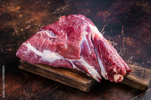 Raw lamb mutton thigh on butcher table. Dark background. Top view