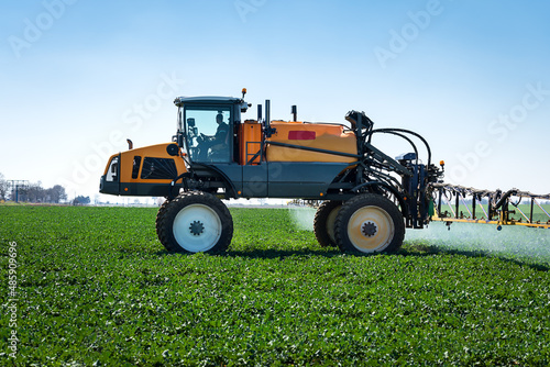Aerial image of tractor spraying soil and young crop in springtime in field.