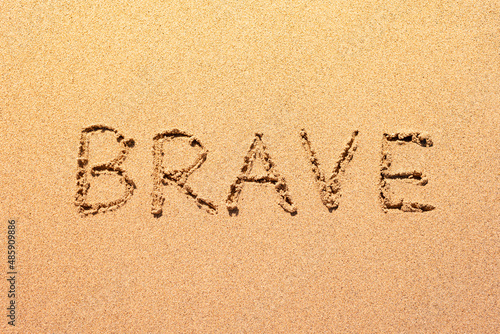 Photo Brave word abstract written in the sand beach