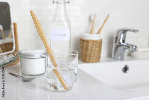 Cleaning a toothbrush with white vinegar, water and baking soda solution on the bathroom sink. Natural desinfection.