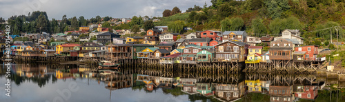 Ein Panorama der Stadt von Castro auf Chiloé, mit den bunten, hölzernen Stelzenhäuser, welche sich im seichten Wasser spiegeln photo