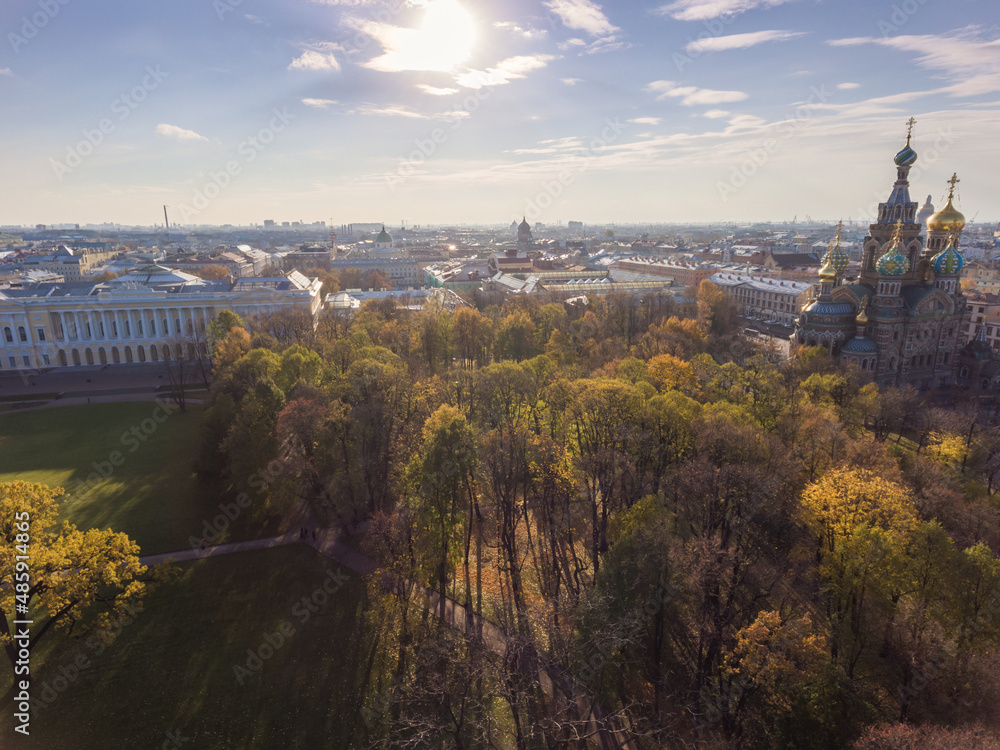 Aerial view of the cathedral Church of the Savior on Blood and park Mikhaylovskiy at sunset, golden dome, roofs of St. Petersburg, shadows of trees, autumn, 