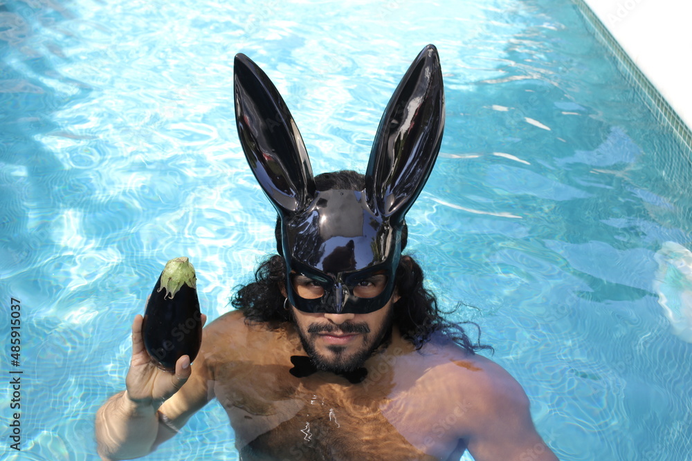 Seductive shirtless muscular man wearing bunny mask in swimming pool ...