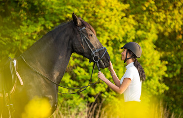 Young woman with her horse in evening sunset light. Outdoor photography with fashion model girl.