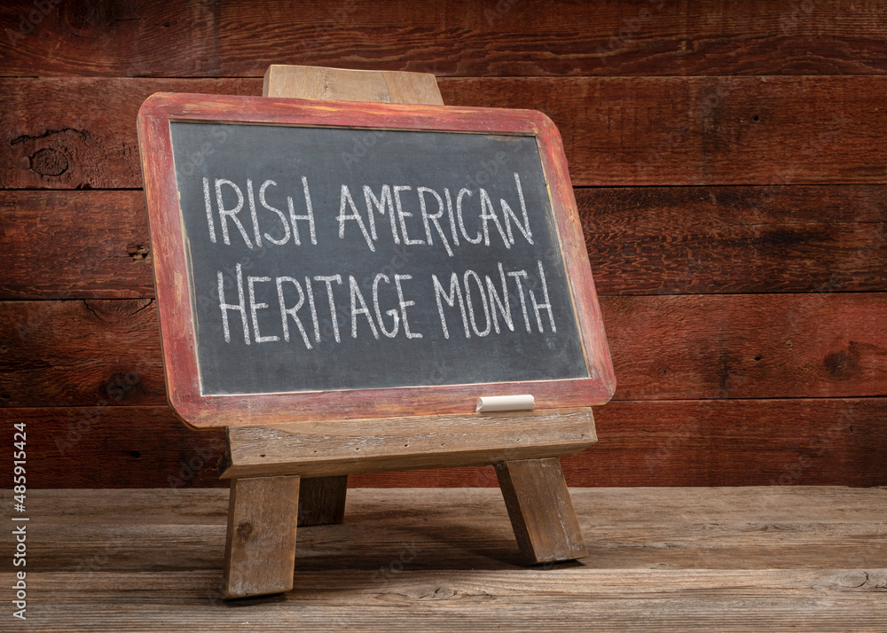 Irish American Heritage Month - white chalk handwriting on a slate blackboard  against a rustic weathered wood background, reminder and education about annual monthly event