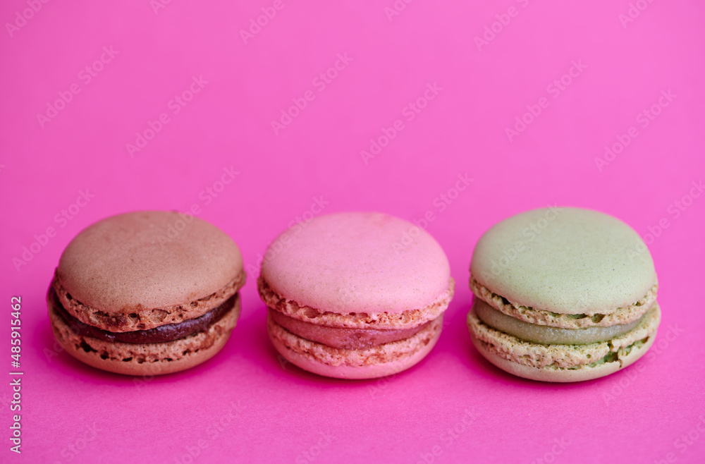 three colored macaroons on pink background with copy space three colored macaroons on pink background with copy space