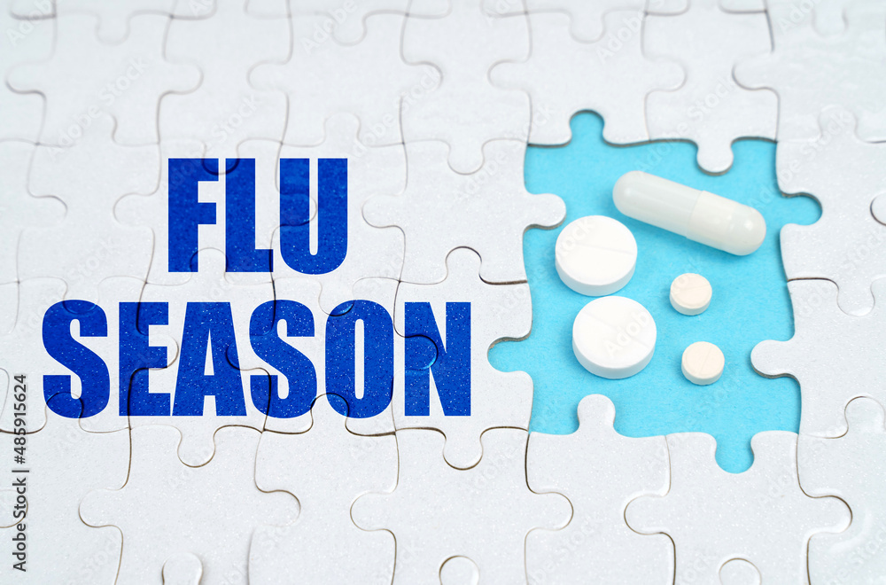 Fototapeta premium On the puzzles there is an inscription - FLU SEASON, on a blue background pills.