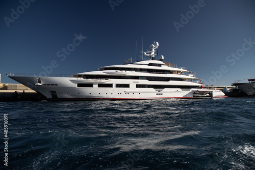 The left board of huge yacht in port of Monaco at sunny day, glossy board of the motor boat, the chrome plated handrail, megayacht is moored in marina, sun reflection on glossy board © Vladimir Drozdin