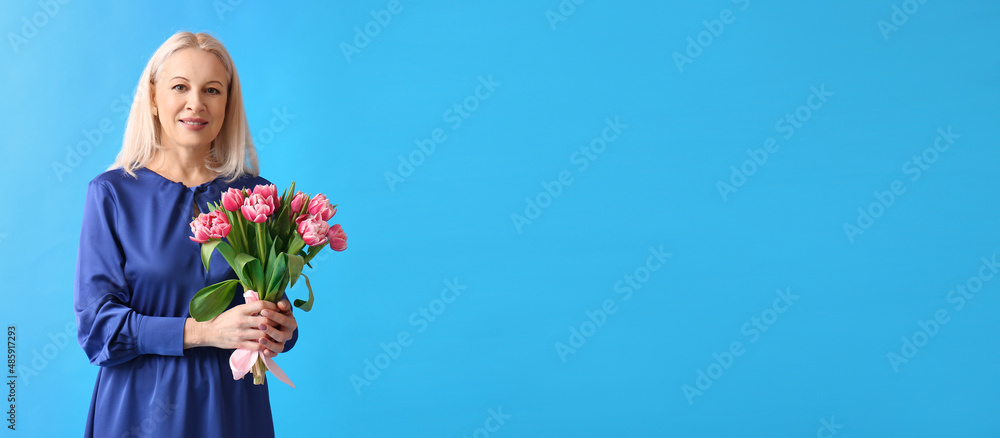 Mature woman with bouquet of tulips on blue background with space for text Mature woman with bouquet of tulips on blue background with space for text