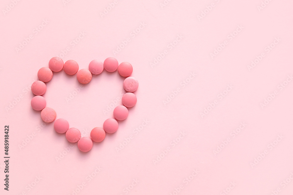 Heart made of pills on pink background