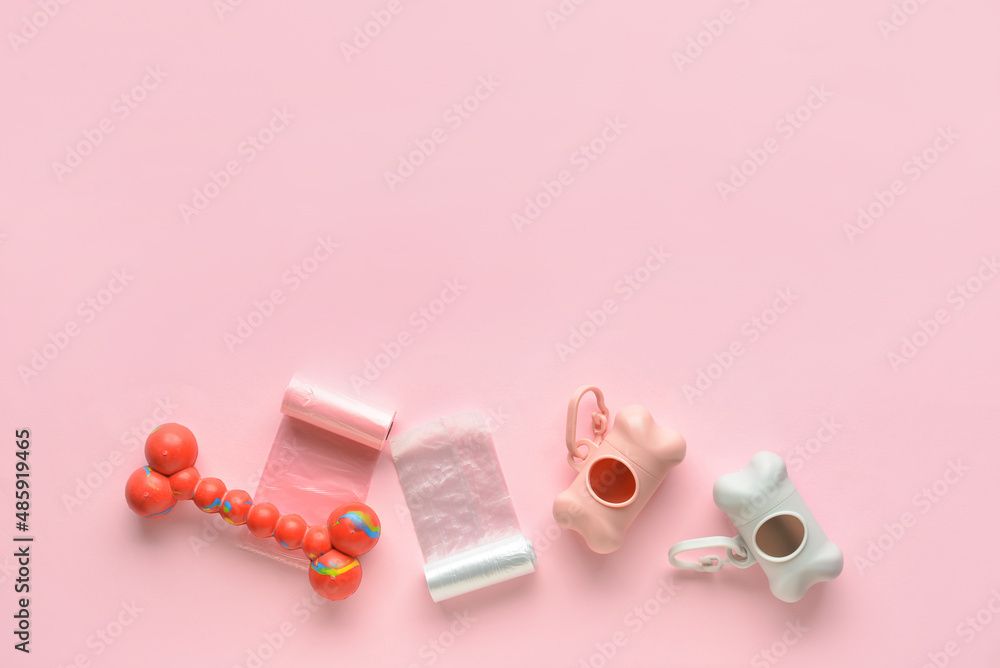 Dispensers with pet waste bags and toy on pink background Dispensers with pet waste bags and toy on pink background