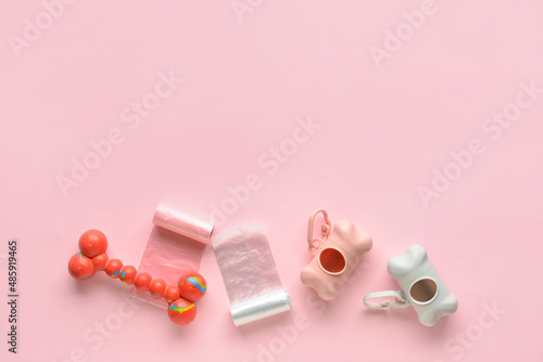 Dispensers with pet waste bags and toy on pink background © Pixel-Shot