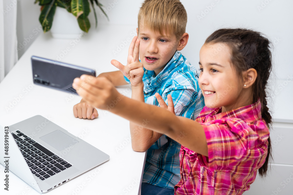 Cute children use laptop for education, online study, home studying, Boy and Girl have homework at distance learning. Lifestyle concept for home schooling. Cute children use laptop for education, online study, home studying, Boy and Girl have homework at distance learning. Lifestyle concept for home schooling.