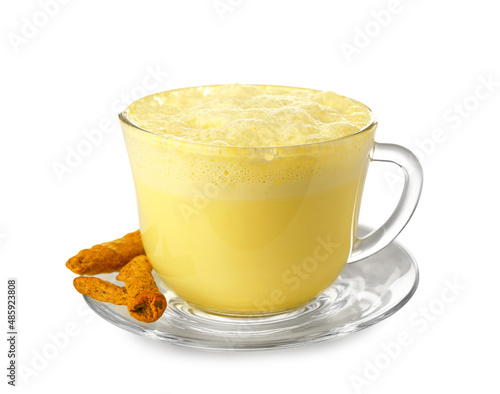 Glass cup of tasty turmeric latte and roots on white background