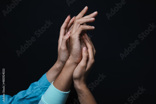 Male and female hands on dark background. Polyamory concept photo