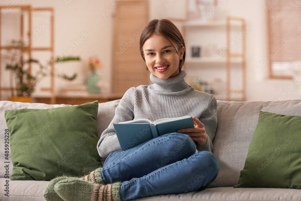 Beautiful young woman with book on sofa at home Beautiful young woman with book on sofa at home