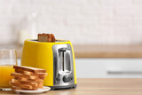 Yellow toaster with bread slices on table in modern kitchen