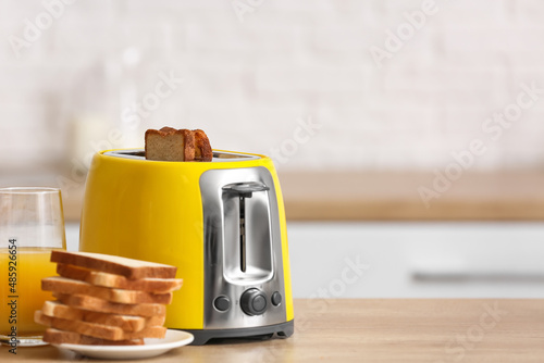 Yellow toaster with bread slices on table in modern kitchen