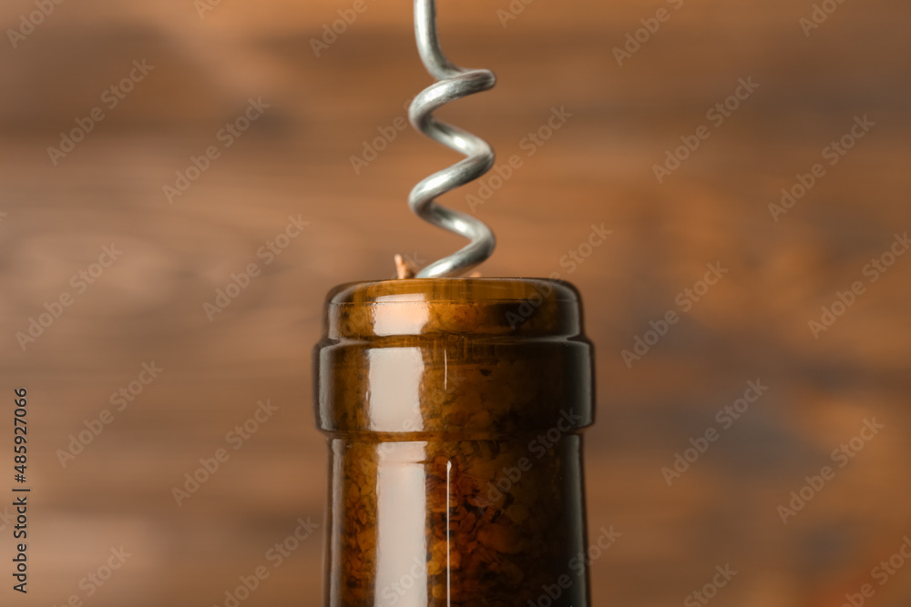 Bottle of wine and corkscrew on blurred background, closeup Bottle of wine and corkscrew on blurred background, closeup