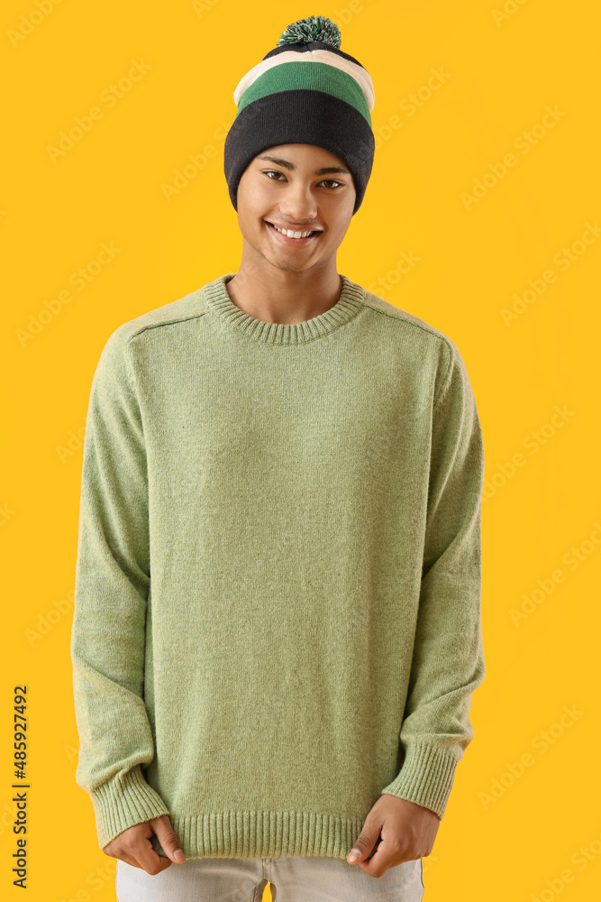 Handsome African-American guy in knitted sweater on yellow background Handsome African-American guy in knitted sweater on yellow background