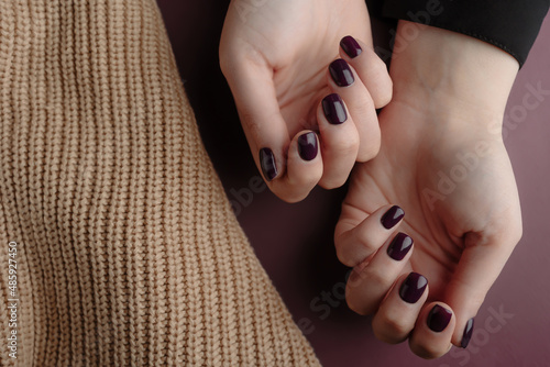 Woman showing her beautiful  manicure near a beige wool material. Trendy square nails Manicure. Manicure beauty salon concept. Hands after getting professional manicure in beauty salon, closeup.