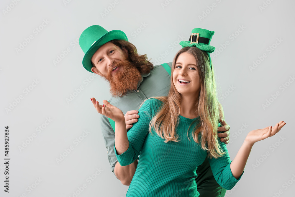 Happy young couple in hats on light background. St. Patrick's Day celebration Happy young couple in hats on light background. St. Patrick's Day celebration