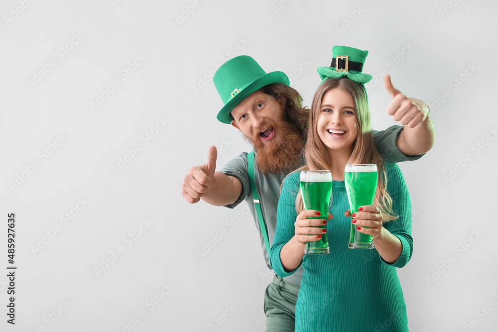 Happy young couple with glasses of beer on light background. St. Patrick's Day celebration Happy young couple with glasses of beer on light background. St. Patrick's Day celebration