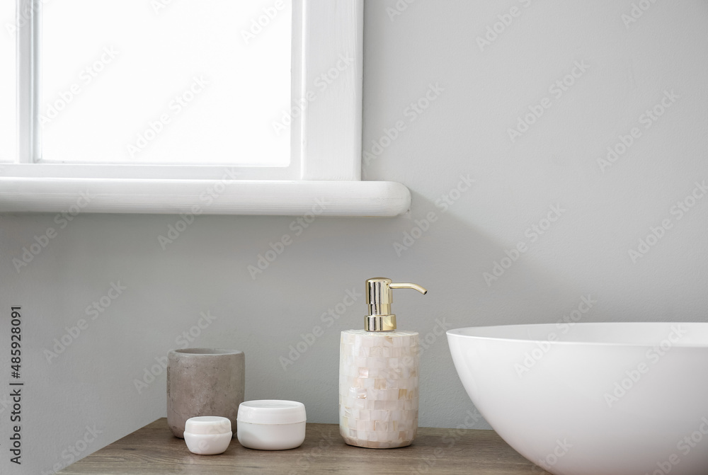 Fototapeta premium Table with sink and bath accessories near light wall