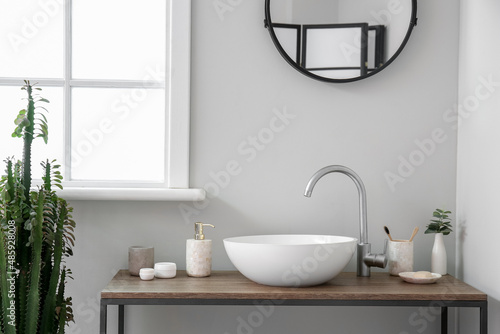 Table with sink and bath accessories near light wall