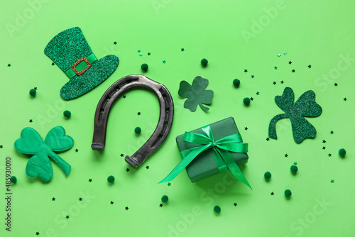 Horseshoe with gift and decor on color background. St. Patrick's Day celebration photo