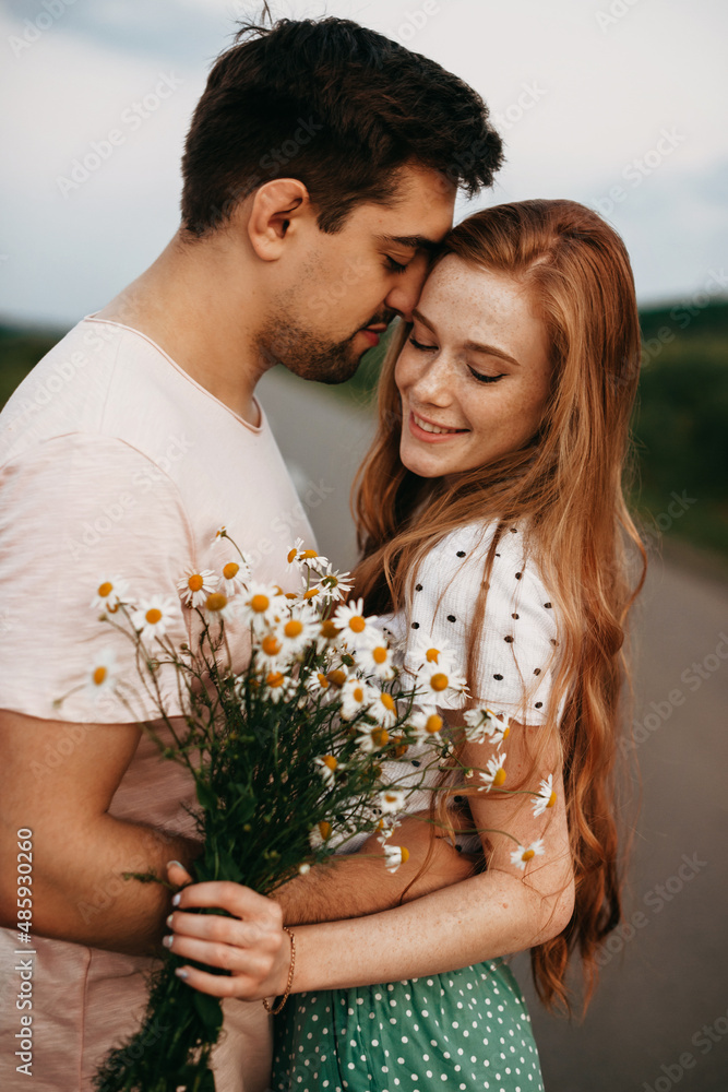 Couple of lovers in the middle of a country road holding each other by hand. Portrait of a girl with a bouquet of daisies. Beautiful female person. Beautiful Couple of lovers in the middle of a country road holding each other by hand. Portrait of a girl with a bouquet of daisies. Beautiful female person. Beautiful