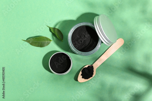 Cuadro en lienzo Jar with activated charcoal tooth powder on green background