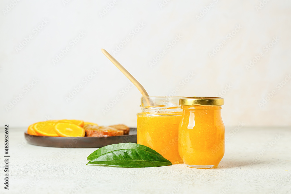 Fototapeta premium Glass jars of tasty orange jam on light background