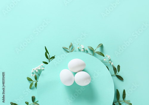 Composition with Easter eggs and green branches on turquoise background