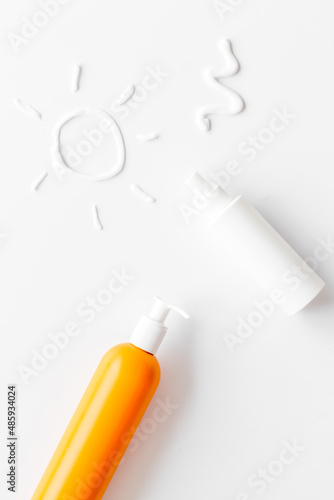 Sunscreen in bottles flatlay with sun made of white cream