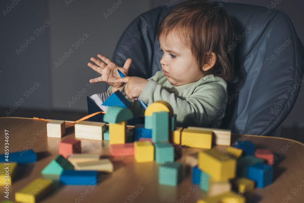 Baby girl playing with connecting toy cubes at home. Children education. Wooden toys. Kids play. Wooden desk, table. Baby girl playing with connecting toy cubes at home. Children education. Wooden toys. Kids play. Wooden desk, table.