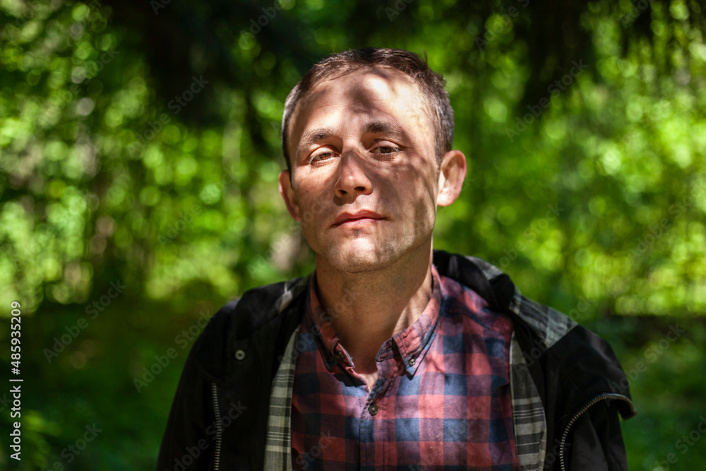 Portrait of guy in woods. Man in nature. Face is shaded by leaves. Man dreams. Brooding man. Young European and student. Portrait of guy in woods. Man in nature. Face is shaded by leaves. Man dreams. Brooding man. Young European and student.