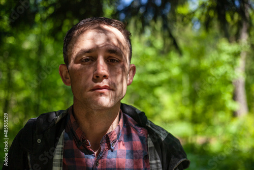Portrait of guy in woods. Man in nature. Face is shaded by leaves. Man dreams. Brooding man. Young European and student.