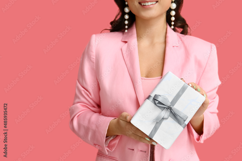 Young woman holding gift box on pink background, closeup. International Women's Day Young woman holding gift box on pink background, closeup. International Women's Day