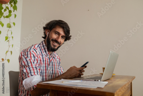Young business man working at home with laptop and papers on desk. Home office concept.