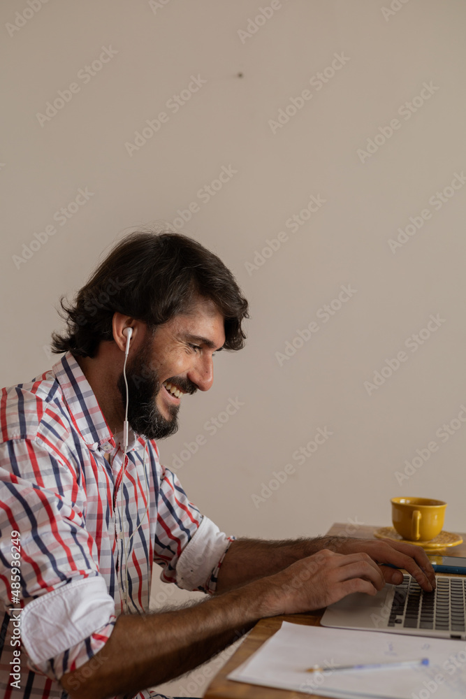 Young business man working at home with laptop on a brown arm chair. Home office concept. Young business man working at home with laptop on a brown arm chair. Home office concept.